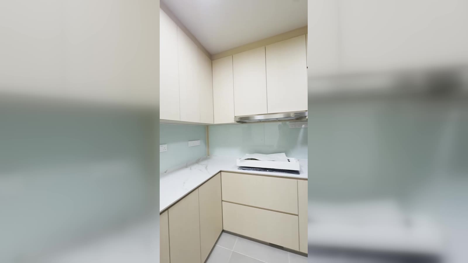 Finished L-shape BTO kitchen with cream handleless doors, marble-effect quartz worktop, mint glass backsplash and slim stainless hood — Bidadari BTO carpentry